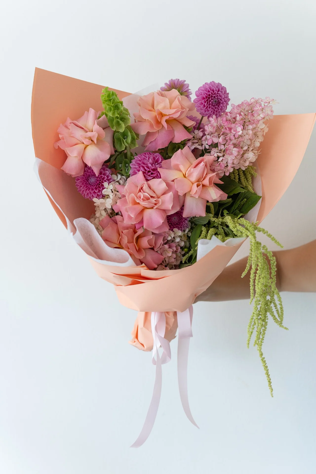 Peach-wrapped bouquet of roses, dahlias and hydrangea
