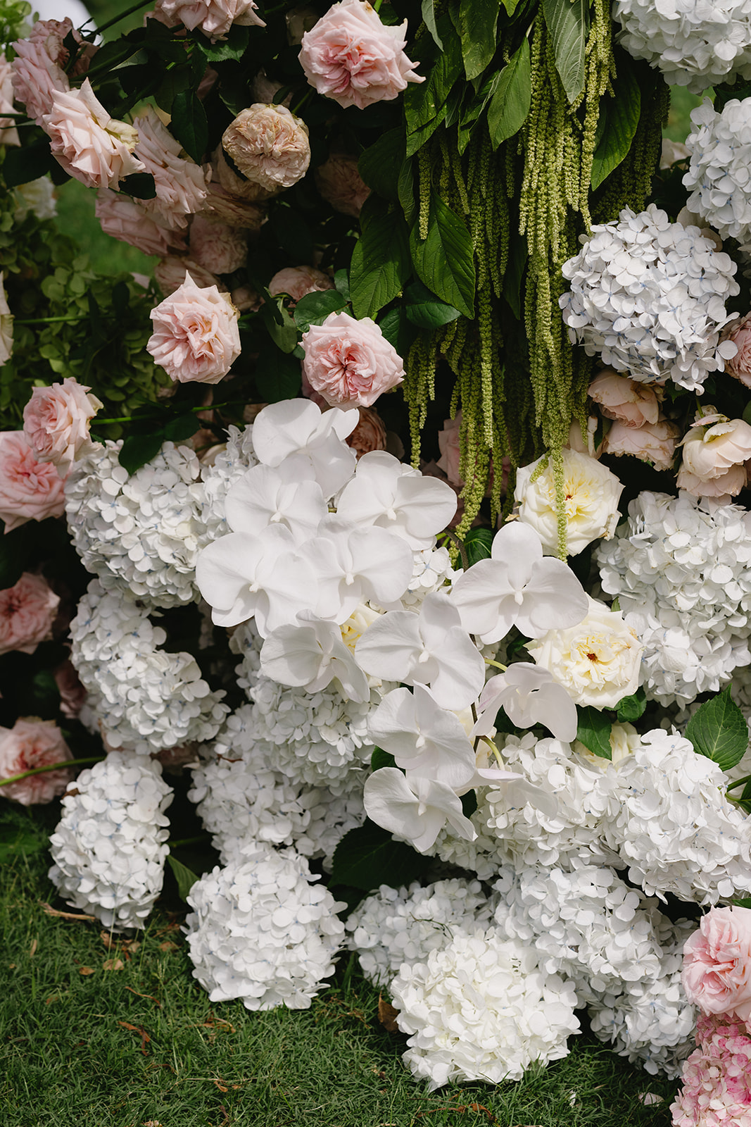Close detail of the ceremony meadow with white hydrangeas, phalaenopsis orchids, roses and hanging green amaranthus